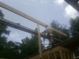 Carpenter setting a ridge beam over a new addition frame — Ice Dam Removal by Roofing Brothers in Grant