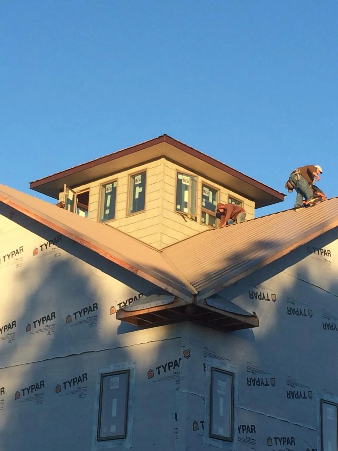 Roofers working around a rooftop cupola on a new metal roof at sunset — Roof Waterproofing in Grant by Roofing Brothers